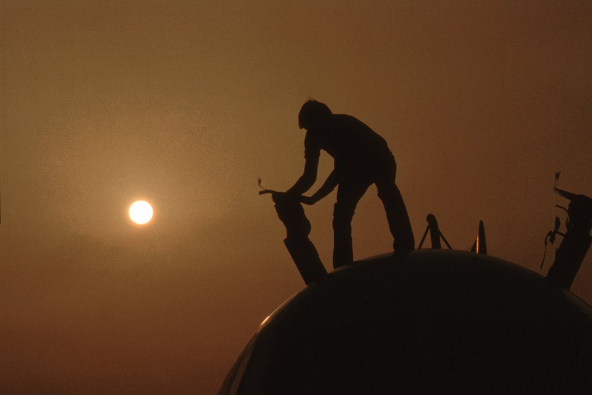 Silhouette of Don Stone performing maintenance atop the NCAR Electra aircraft in Kuwait (1991), Photo Courtesy of Robert Bumpas.png