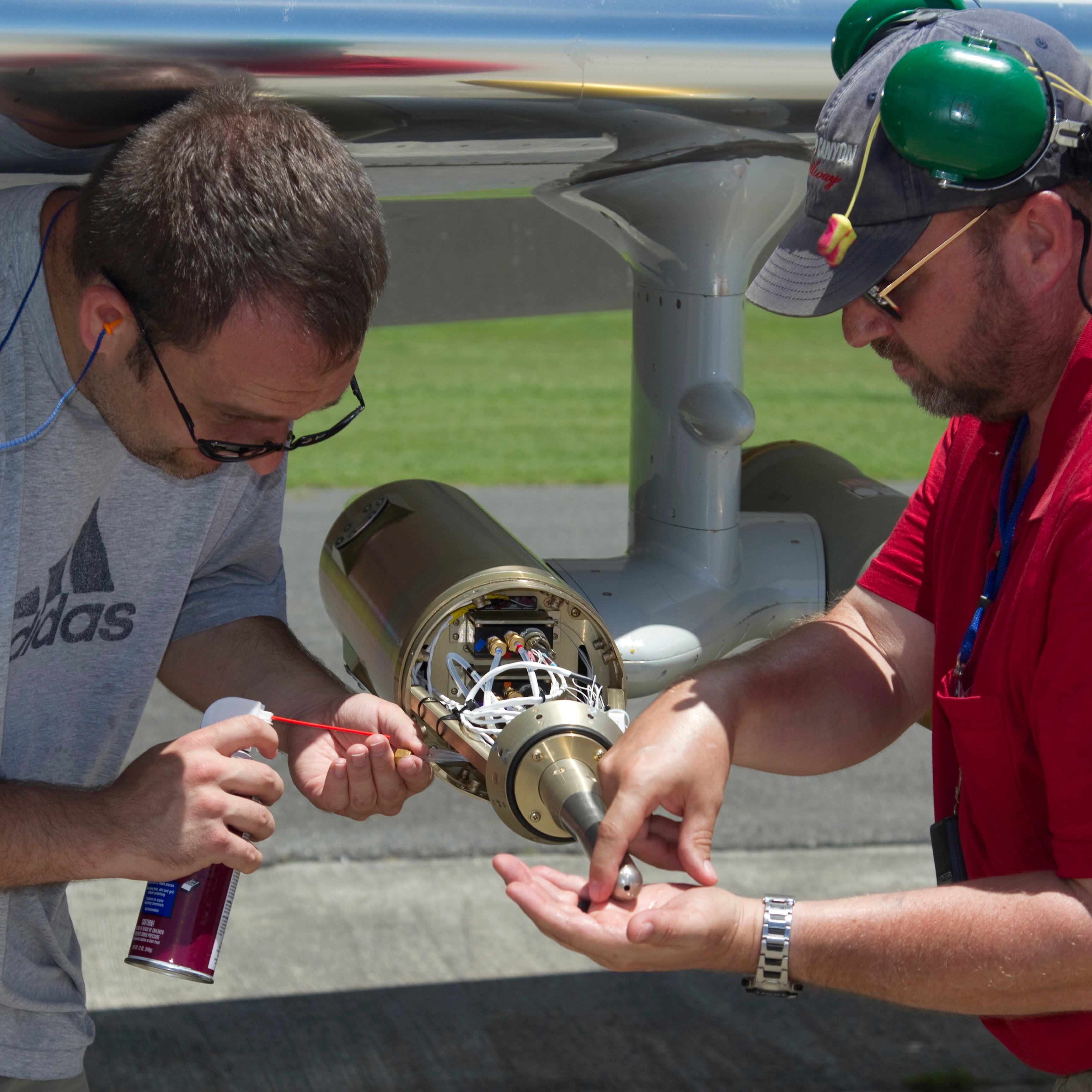 Two airplane mechanics working on plane.